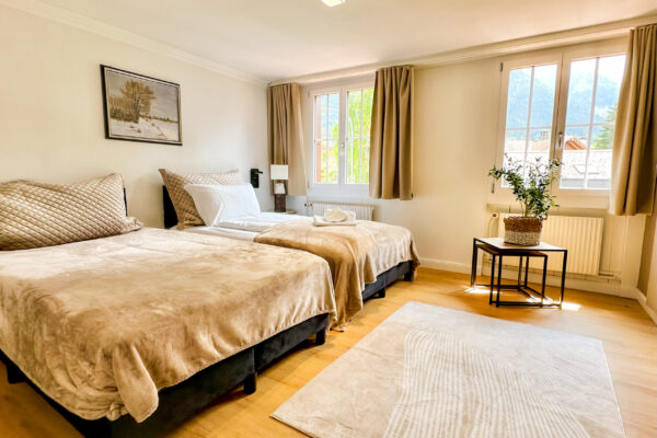 Chalet Simmi-60 Chalet Simmi in Wimis in der Schweiz: Schalfzimmer, geräumiges Gästezimmer, ein kuscheliges Bett mit warmen Licht, einer Couch, Kerzen, Tischen