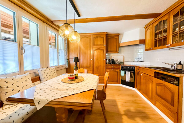 Chalet Simmi-73 Einladende warme Küche mit Sitzmöglichkeiten, Herd, Ofen, Waschbecken und voller Ausstattung im alpiner Flair